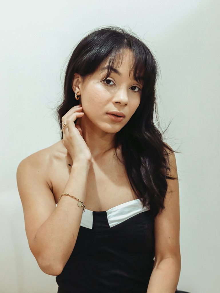 Sophisticated portrait showcasing a woman in a stylish black and white dress against a neutral background.