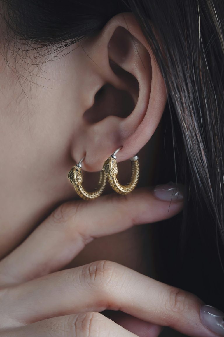 Elegant gold hoop earrings on a woman's ear with a focus on minimalist design and style.