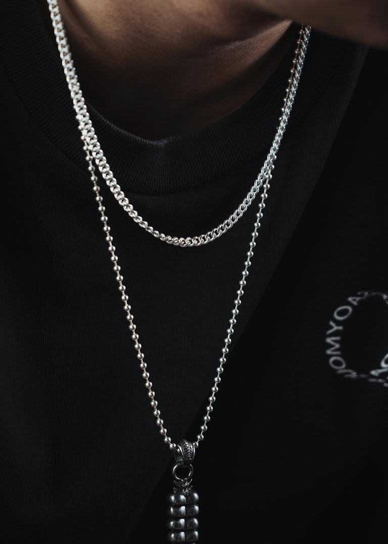 Close-up of a stylish silver pendant necklace worn by a model in black