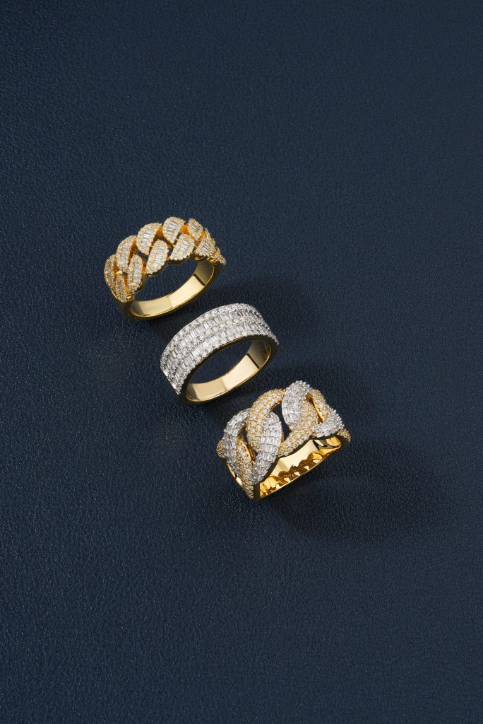 Three elegant golden rings with diamonds against a dark textured surface, showcasing luxury and style.