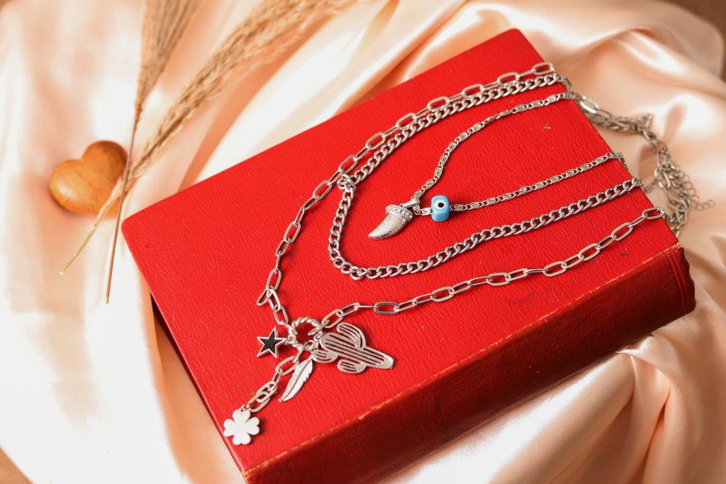 Stylish silver necklace with charms on a vibrant red book, perfect for fashion editorials.