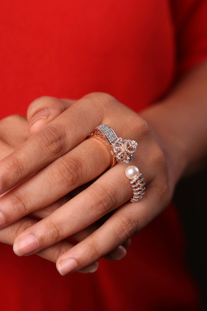 Close-up of a woman's hand adorned with elegant rings against a red background.