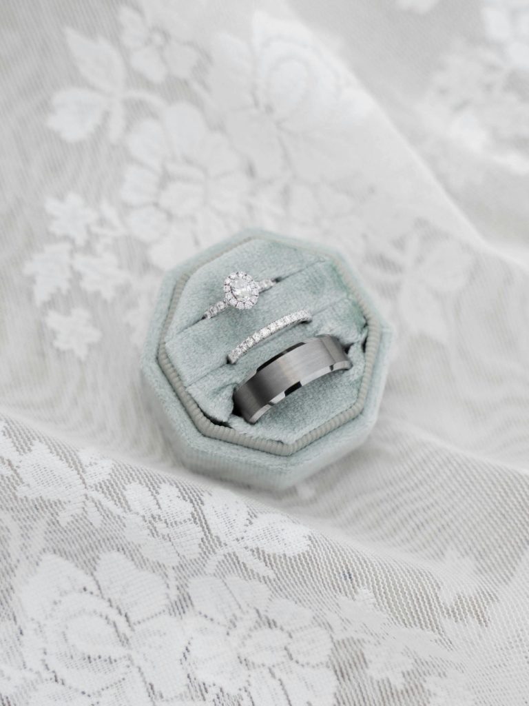 Close-up of elegant wedding rings in a box on white lace fabric.