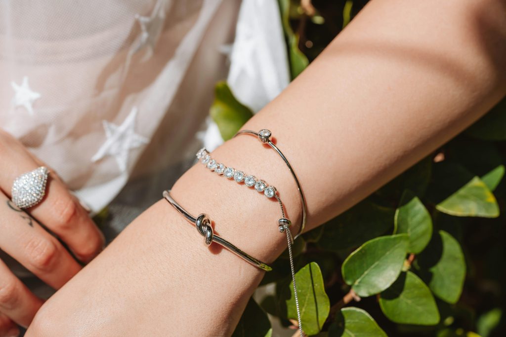 Close-up of elegant silver jewelry on wrist, featuring bracelets and a ring.
